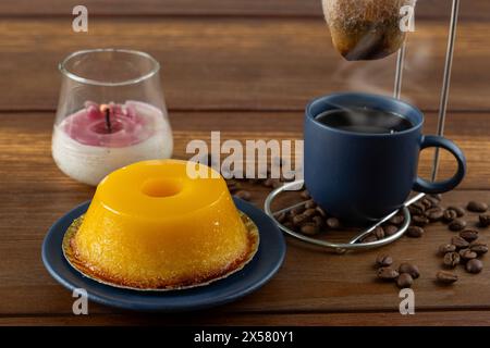 Kleiner Quindim, traditionelles brasilianisches Süßes, neben einer Tasse Kaffee und einer Kerze 4. Stockfoto