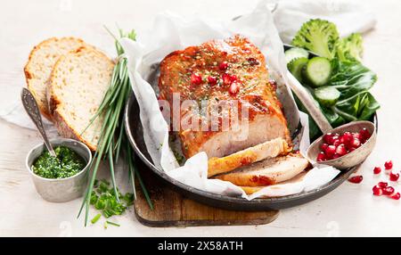 Gebackener Schinken in Scheiben mit Salat auf hellem Holzhintergrund. Traditionelles kulinarisches Konzept. Stockfoto