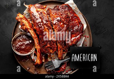 Heiße gegrillte Spare Ribs von einem Sommer BBQ serviert auf einem Teller mit Sauce. Draufsicht. Stockfoto
