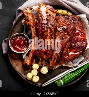 Heiße gegrillte Spare Ribs von einem Sommer BBQ serviert auf einem Teller mit Sauce. Draufsicht. Stockfoto