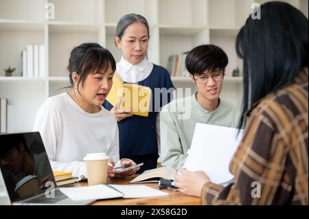 Eine strenge asiatische Professorin oder Lehrerin unterrichtet ihre Schüler im Klassenzimmer. Eine Gruppe von Studenten einer Universität, die mit einem Reifen f Stockfoto