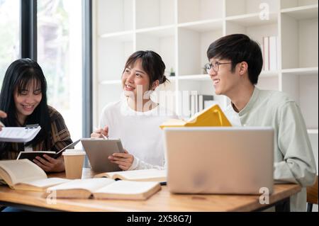 Eine Gruppe fröhlicher asiatischer Universitätsstudenten lernt gerne mit ihrem Lehrer im Klassenzimmer. Die Schüler hören ihren Lehrern zu, was sie erklären Stockfoto