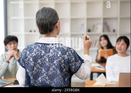 Ein Rückbild einer Reifen asiatischen Lehrerin, die ihren Schülern im Klassenzimmer einen Vortrag hält. universität, Bildungskonzept Stockfoto