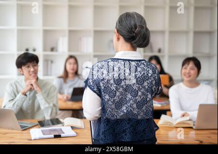 Ein Rückbild einer Reifen asiatischen Lehrerin, die ihren Schülern im Klassenzimmer einen Vortrag hält. universität, Bildungskonzept Stockfoto