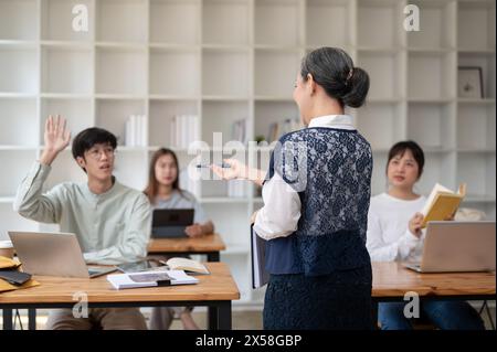 Ein Rückbild einer Reifen asiatischen Lehrerin, die ihren Schülern im Klassenzimmer einen Vortrag hält. universität, Bildungskonzept Stockfoto