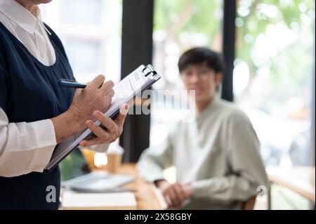 Eine reife asiatische Lehrerin, die ihrer Schülerin in der Klasse hilft und schwierige mathematische Probleme erklärt. Bildungskonzept Stockfoto