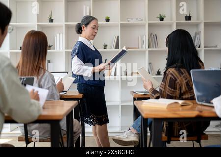 Eine professionelle, reife asiatische Lehrerin oder Professorin unterrichtet im Klassenzimmer, hält ihren Schülern einen Vortrag, erklärt eine Lektion oder diskutiert Stockfoto