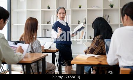 Eine professionelle, reife asiatische Lehrerin oder Professorin unterrichtet im Klassenzimmer, hält ihren Schülern einen Vortrag, erklärt eine Lektion oder diskutiert Stockfoto