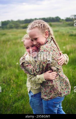 Schwestern umarmen und schützen sich gegenseitig vor dem Wind auf dem Feld Stockfoto