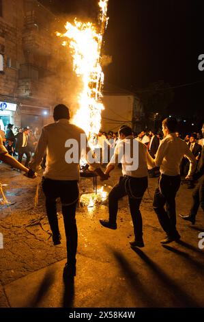 Orthodoxe jüdische Männer singen und tanzen auf der Straße neben einem Lagerfeuer bei einem traditionellen lag B'Omer-fest in Jerusalem, Israel. Stockfoto