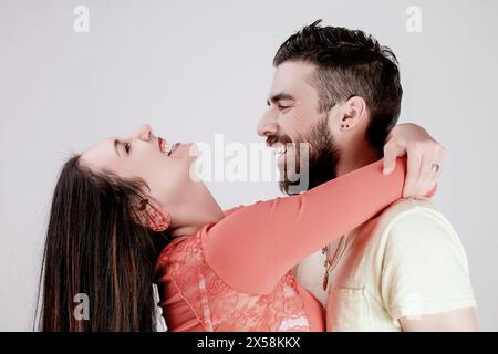 Enge Interaktion zwischen einer fröhlichen jungen Frau und einem lächelnden Mann, beide in lässiger Kleidung, genießen einen Moment des Lachens und der Nähe Stockfoto