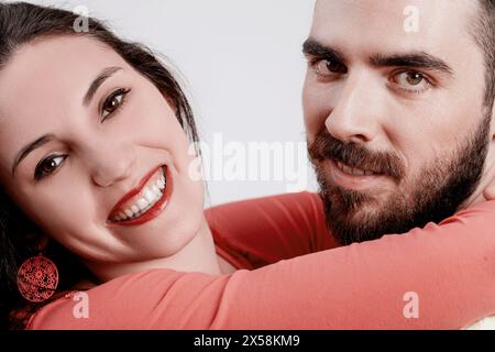 Enge Interaktion zwischen einer fröhlichen jungen Frau und einem lächelnden Mann, beide in lässiger Kleidung, genießen einen Moment des Lachens und der Nähe Stockfoto