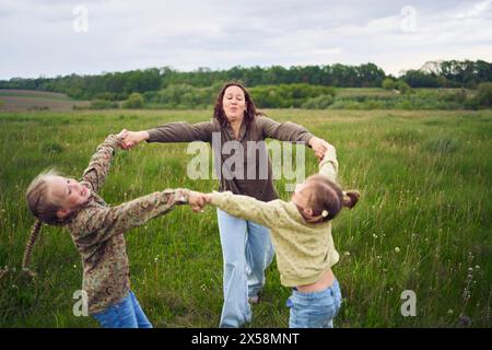 Mutter und zwei Schwestern kreisen auf dem Feld und halten Hände Stockfoto