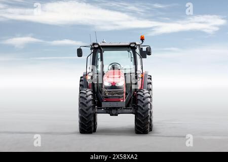 Vorderansicht des roten modernen Radtraktors isoliert auf hellem Hintergrund mit Himmel Stockfoto