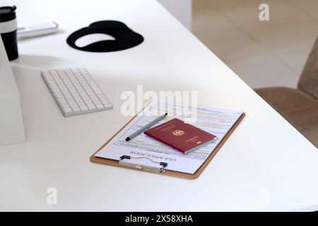 Nahaufnahme eines Bürotisches mit Visumantragsunterlagen und einem deutschen Reisepass Stockfoto