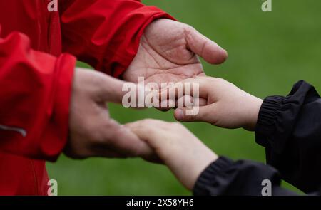 SYMBOL - 07. Mai 2024, Sachsen, Leipzig: ILLUSTRATION - Ein Vater hält die Hände seines Sohnes. Neben seiner religiösen Bedeutung als Himmelfahrt ist dieser Tag in vielen Ländern auch Vatertag genannt. Foto: Hendrik Schmidt/dpa Stockfoto