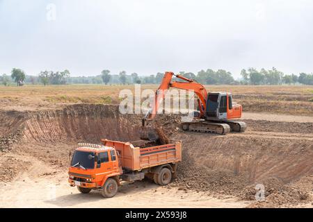 Ein Bagger lädt Boden auf den hinteren Teil eines Muldenkippers auf dem Feld. Stockfoto