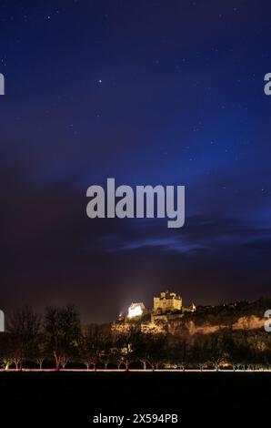 Beynac-et-Cazenac, Frankreich - 6. Mai 2024: Einbruch der Dunkelheit über dem Chateau de Beynac in der Region Dordogne in Frankreich mit Lichtspuren von Autos im Vorland Stockfoto