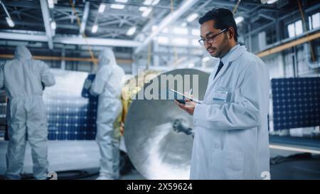 Team von Ingenieuren arbeitet an Satellite Construction, Wissenschaftler verwendet Tablet Computer. Aerospace Agency: Diverse Gruppe von Spezialisten, die Raumfahrzeuge für Weltraumforschungsmissionen entwickeln Stockfoto