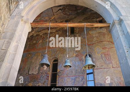 Drei Glocken und mittelalterliches Wandgemälde an der Fassade der Kirche der Himmelfahrt in Vardzia Cave City auf dem Erusheti Mountain, Südgeorgien Stockfoto