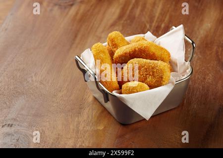 Eine Portion Chicken Nuggets serviert in einem einzigartigen Blechbehälter mit weißer Serviette auf einem Holztisch Stockfoto