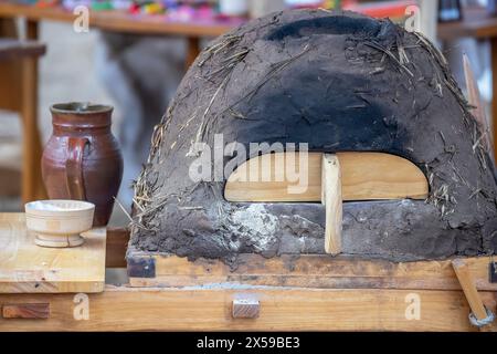 Keramikkkanne, Schüssel mit Mehl und mittelalterlicher Lehmofen zum Brotbacken aus der Nähe, Geschirr auf einem Holztisch, mittelalterlicher Lebensstil, Stillleben. Stockfoto