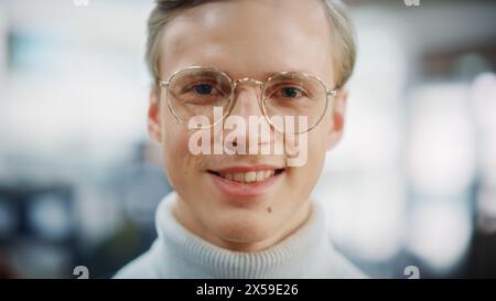 Nahaufnahme Porträt eines hübschen jungen blonden Mannes, der stilvolle Brillen trägt und charmant lächelt. Stockfoto