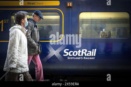 Dateifoto vom 05/22 von Pendlern, die an einem ScotRail-Zug an Edinburghs Waverley Station vorbeilaufen. Die Abschaffung der Spitzenpreise begann im Oktober letzten Jahres und wurde vor kurzem bis Ende Juni verlängert, wobei die schottische Regierung entscheiden sollte, ob sie weiter anhalten wird. Der erste Minister John Swinney sagte, dass die Regelung "sehr effektiv" sei, aber er stellte fest, dass "alles bezahlt werden muss". Ausgabedatum: Mittwoch, 8. Mai 2024. Stockfoto