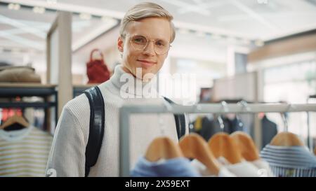 Gutaussehende männliche Kunden kaufen im Bekleidungsgeschäft und wählen stilvolle Kleidung. Porträt des attraktiven jungen Mannes in modischem Geschäft, trendigen Marken, New Designers Collection aus nachhaltigem Material Stockfoto