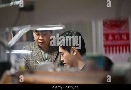 (240508) -- TIANJIN, 8. Mai 2024 (Xinhua) -- Ma Sai (R) spricht mit seiner Mutter über filigrane Mosaikkunst in seinem Atelier im Dorf Liuzhuang im Bezirk Wuqing in Tianjin, Nordchina, 19. März 2024. MA's filigrane Mosaic Art, ein immaterielles Kulturerbe der Stadt in Tianjin, zog die Aufmerksamkeit des ganzen Landes auf sich, als ein damit hergestelltes Accessoire während der Frühlingsfestgala des Jahres des Drachen, die vom chinesischen Zentralfernsehen inszeniert wurde, auf den Kopf einer chinesischen Schauspielerin erschien. auch CCTV genannt. Filigrane Mosaikkunst, erstmals in der Frühlings- und Herbstzeit (770 v. Chr. -476 v. Chr.), begrüßt Stockfoto