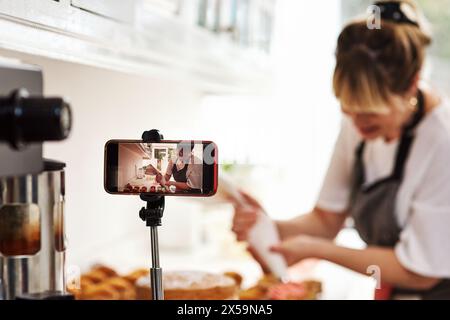 Frau, Kocher oder Influencer mit Telefon für soziale Medien, Rezepte oder Zutaten für Mahlzeiten in der Küche oder zu Hause. Fotografie, Koch oder Bäcker mit Essen für Stockfoto