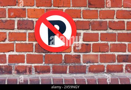 Rotes Kreisverkehrsschild mit verbotenem Parken an roter Backsteinmauer Stockfoto