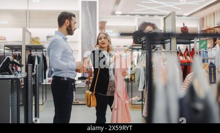 Schöne weibliche Kunden kaufen im Bekleidungsgeschäft, Retail Sales Associate hilft Ihnen mit Rat. Vielfältige Menschen im Modegeschäft, die sich für stilvolle Kleidung entscheiden, bunte Marke mit nachhaltigem Design Stockfoto