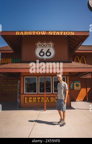 Junger Mann an der Barstow Station an der Route 66, Freizeitkleidung, McDonald's und U-Bahn-Schilder. Stockfoto