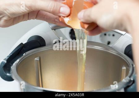 Ein Ei zum Backen in einen Mixer knacken, weißer Standmixer, Metallschüssel, auf Action fokussiert Stockfoto