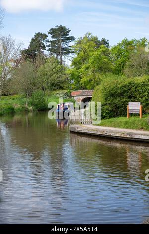 Ein Schmalboot, das nahe dem Eingang eines Yachthafens in der Nähe von Ellesmere in Shropshire vor Anker liegt und von Bäumen und Büschen umgeben ist. Stockfoto