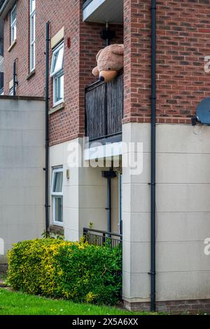 Der riesige Teddybär sucht nach allen Welten, als ob er von diesem Balkon oben fliehen will. Stockfoto