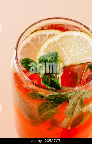 Lebendige Beeren-Orangen-Limonade garniert mit frischen Minzblättern und Zitronenscheiben, serviert in einem Glas mit Eis; perfekt für einen heißen Tag. Stockfoto