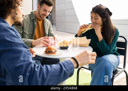Gruppe von Freunden, die frische Mahlzeiten von einem Food Truck in einem Sitzbereich im Freien genießen Stockfoto