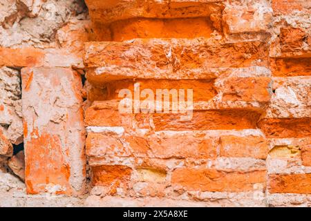 Dieses Bild zeigt die komplizierten Details einer verwitterten Ziegelwand und zeigt die raue Textur und die leuchtenden Orangetöne. Stockfoto