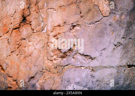 Nahaufnahme einer verwitterten Wand mit einer Mischung aus rissigem Putz und freiliegendem Mauerwerk, mit komplizierten Texturen und Mustern. Stockfoto