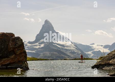 Ein ruhiges Bild, das ein individuelles Paddelboarding auf einem ruhigen Bergsee mit dem berühmten Matterhorn in den Schweizer Alpen im Hintergrund zeigt Stockfoto