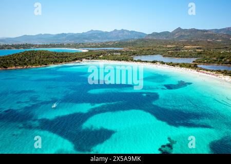 Blick aus der Vogelperspektive auf das atemberaubende türkisfarbene Wasser eines sardischen Strandes, Brandinchi Beach, im Kontrast zu weißem Sand und üppigen Hügeln Stockfoto