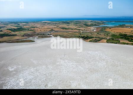 Ein atemberaubendes Luftbild fängt die strukturelle Schönheit der sardischen Salzebenen mit Blick auf die üppige Landschaft und das ferne Meer ein Stockfoto