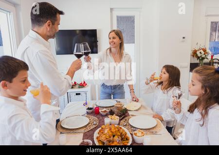 Eine glückliche Familie, die zu Hause ein festliches Weihnachtsessen mit einem wunderschön dekorierten Tisch und einem gebratenen truthahn genießen kann Stockfoto