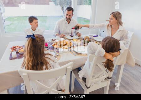 Ein warmes und festliches Familienweihnachtsmenü zu Hause mit Eltern und Kindern, die ein köstliches Abendessen zusammen an einem dekorierten Tisch genießen Stockfoto