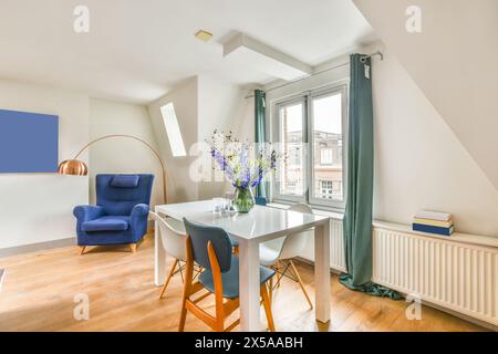 Ein helles und luftiges Apartment im Dachgeschoss mit stilvollen, modernen Möbeln, großen Fenstern und dekorativen Blumen auf einem weißen Tisch. Stockfoto