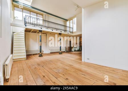 Heller und luftiger, leerer Loft-Bereich mit hohen Decken, freiliegenden Balken, Hartholzfußboden und Zwischengeschoss. Stockfoto