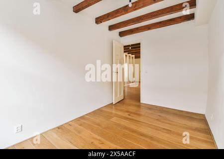 Leeres Zimmer mit poliertem Holzfußboden und sichtbaren Deckenbalken, die ein modernes minimalistisches Interieur schaffen. Stockfoto