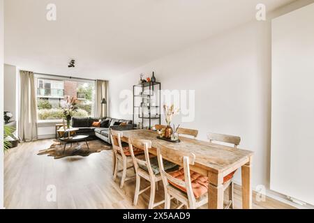 Ein gut beleuchtetes, geräumiges Wohnzimmer, das nahtlos mit einem Essbereich verbunden ist, mit modernen Möbeln und großen Fenstern. Stockfoto